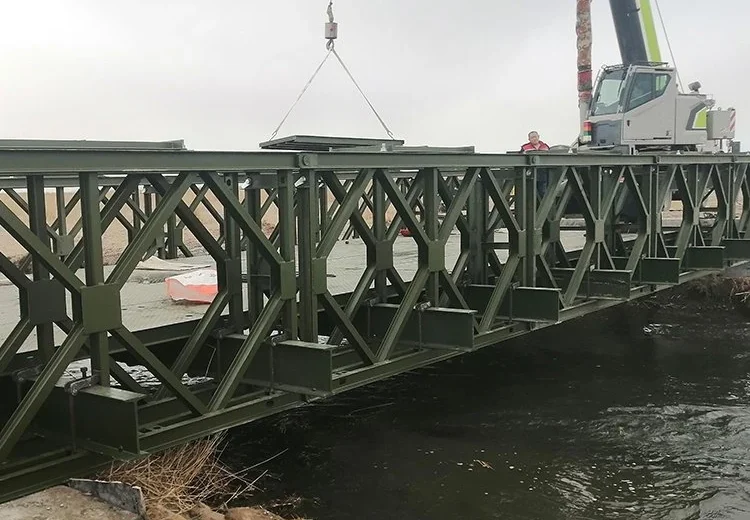 Crane lifting a Bailey bridge deck section into position